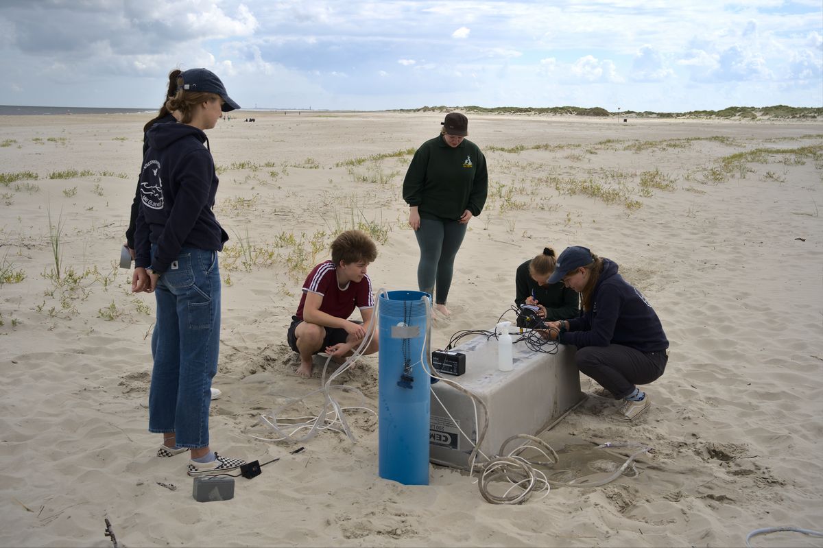 Aus der Tiefe — Frida Pankiewitz — Das Foto zeigt die Probennahme von Porenwasser auf der Insel Spiekeroog. Aus verschiedenen Tiefen wurden Wasserproben genommen, welche im Nachhinein mikrobiologisch untersucht wurden.Die Untersuchungen fanden im Rahmen des Praktikums "Mikrobielle Ökologie" statt. 