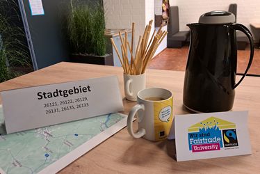 PLz-Frühstück 2024 Auf dem Tisch stehen eine PLZ-Tischkarte, Kaffeekanne und Snacks