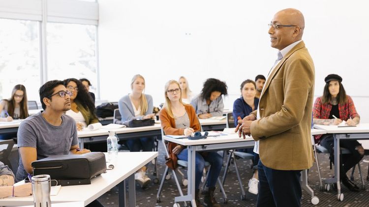 Professor doziert stehend vor Studierenden im Seminarraum