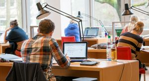 ZSKB-Lernwerkstatt im BIS Eine Person sitzt in der Bibliothek an einem Tisch vor einem Laptop.