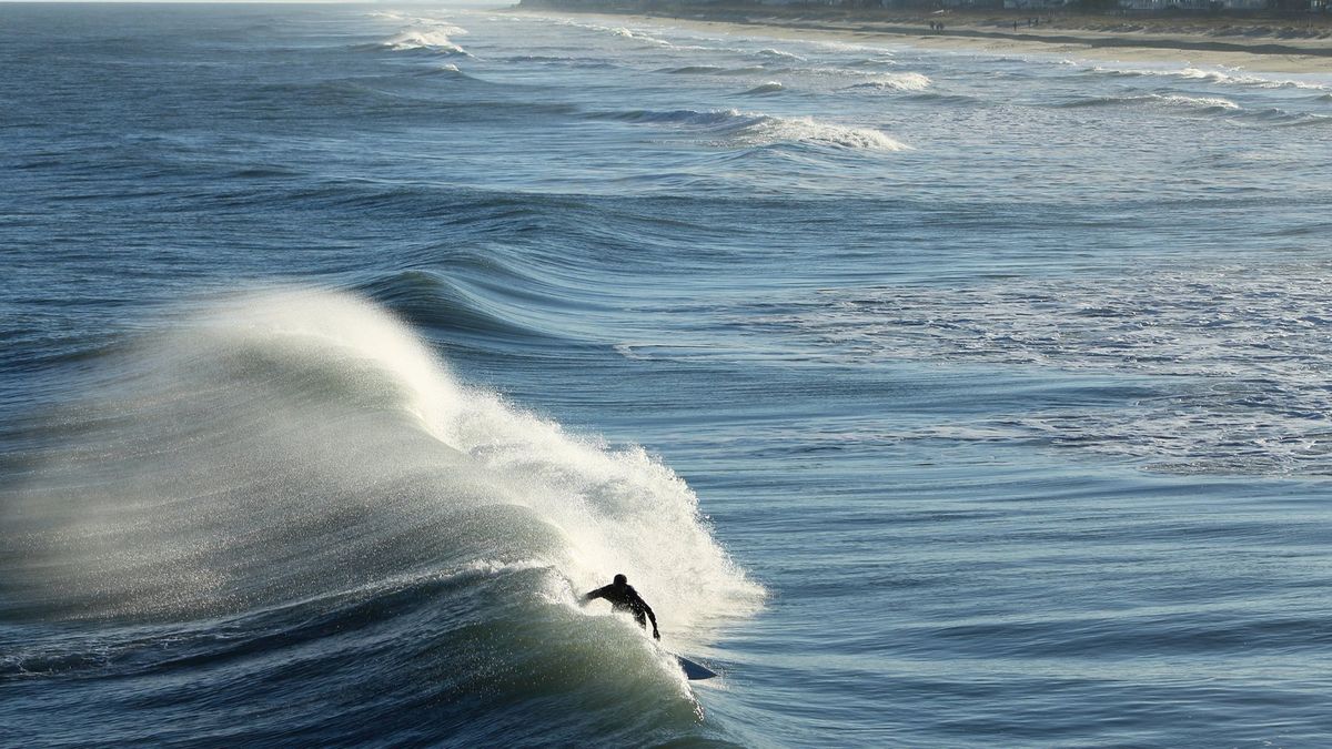 Küste mit einem Surfer im Wasser