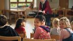 Ein Mädchen mit Cholea-Implantat sitzt in einer Kindergruppe und dreht sich zur Kamera um.