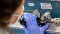 A woman is working on a mechanical device on which a scale can be seen.
