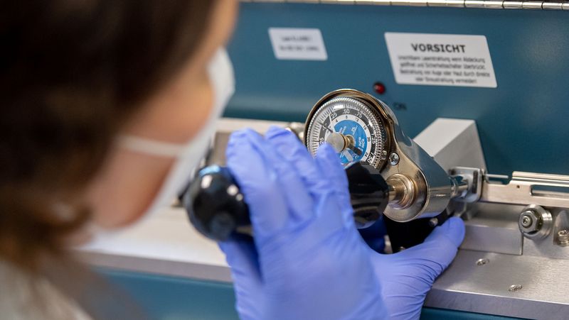 Eine Frau arbeitet an einem mechanischen Gerät, auf dem eine Skala zu sehen ist.