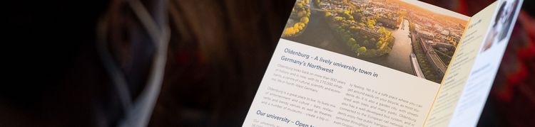 Orientierung fürs Studium Person sieht sich eine Informationsbroschüre an
