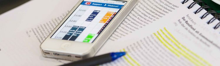 A smartphone with an app interface lies on a text document about Berthold Brecht.
