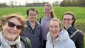Five people in front of a meadow. 