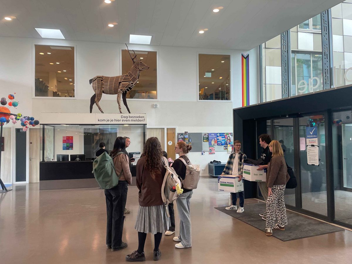 Teaching Across Borders Die Eingangshalle der Schule Stad&Esch mit einer lebensgroßen Tier-Statue und einer Gruppe von jungen Erwachsenen.