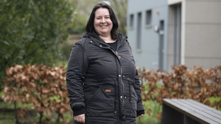 Das Bild zeigt Clara Liehmann. Sie steht hinter dem SSC in einer Regenjacke bei diesigem Wetter. Sie blickt in die Kamera und lächelt dabei.