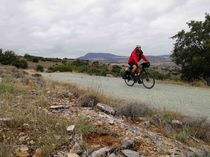 Grünes Reisen  Ein Radfahrer fährt auf einem unbefestigten Weg durch eine hügelige Landschaft.