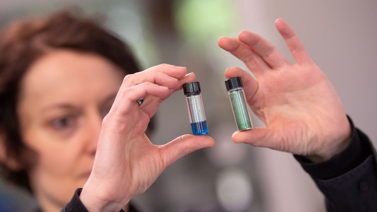 Manuela Schiek hält zwei Fläschchen mit dem Farbstoff in den Händen.