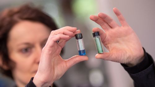 Manuela Schiek hält zwei Fläschchen mit dem Farbstoff in den Händen.