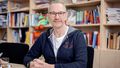 The picture shows Clemens Hillenbrand. He sits at a table in front of a bookshelf and looks into the camera.