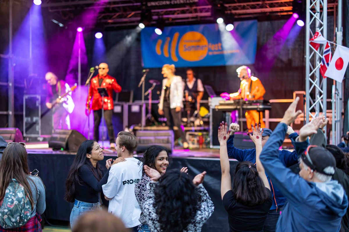 Auftritt einer Band auf dem Sommerfest. Die Personen vor der Bühne wirken begeistert und tanzen zu der Musik.