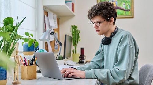 Auf dem Bild ist ein junger Mann im Homeoffice zu erkennen.