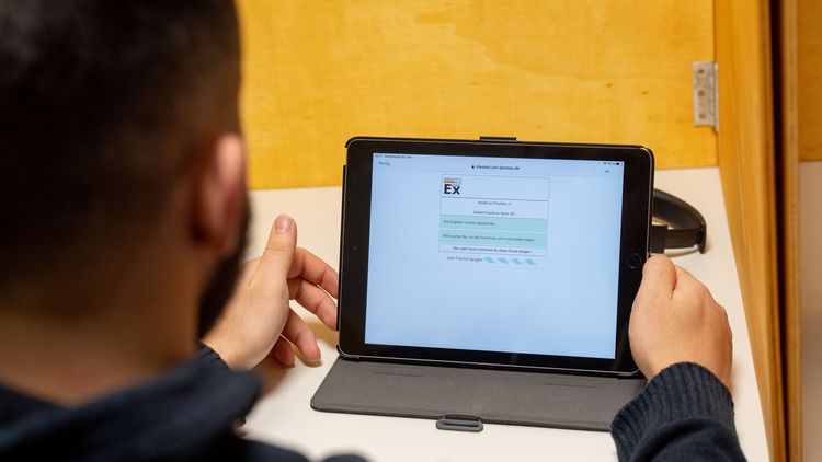 Blick über die Schulter eines Studierenden auf ein Laptop.