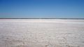 Landscape: Smooth, white background (the salt), blue sky above, in the background a thin, darker stripe on the horizon.