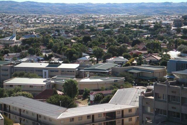 Hauptcampus der Namibia University of Science and Technology Ein Panorama des Campus der Namibia University of Science and Technology (NUST) mit flachen Gebäuden. Im Hintergrund Hügel und eine Stadtlandschaft.