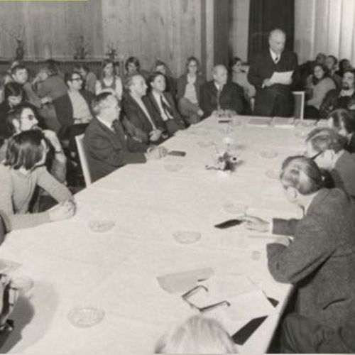 Das Bild zeigt die Gründungsversammlung der UGO. Mehrere dutzend Menschen sitzen in einem Raum und hören einem Sprecher zu.