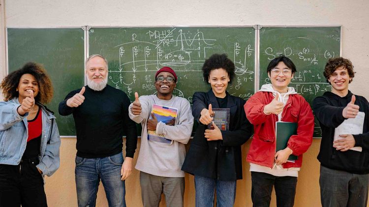 Symbolbild für Lehramt.International Gruppe von Lehrenden vor einer Tafel in einem Klassenzimmer.