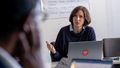 This picture shows Malve von Möllendorf. She is sitting behind a laptop, explaining an issue to someone attending the colloquium.
