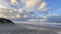 View from the beach towards the sea, dramatic clouds towering in the sky. 