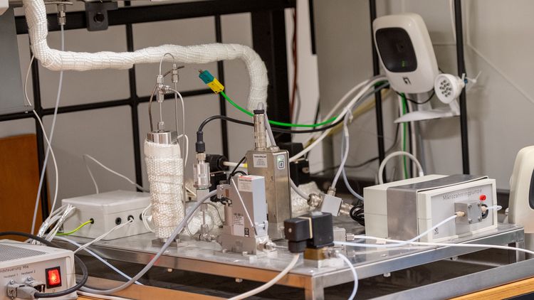 Auf einer Platte befinden sich mehrere metallische Module, die durch Kabel, Schläuche und kleine Röhrchen verbunden sind.