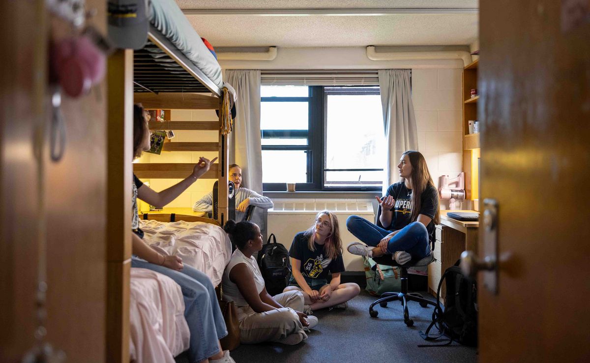 Studierendenwohnheim Studierende sitzen in einem Studierendenwohnheim zusammen und unterhalten sich. Ein Zimmer mit Etagenbett und Schreibtisch.
