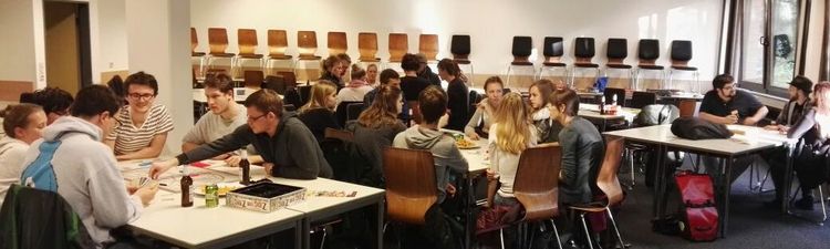 Viele Studierende spielen an großen Tischen