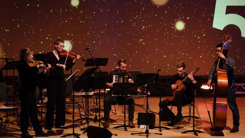 Fünf studentische Musiker*innen mit Geigen, Akkordeon, Gitarra und Kontrabass.