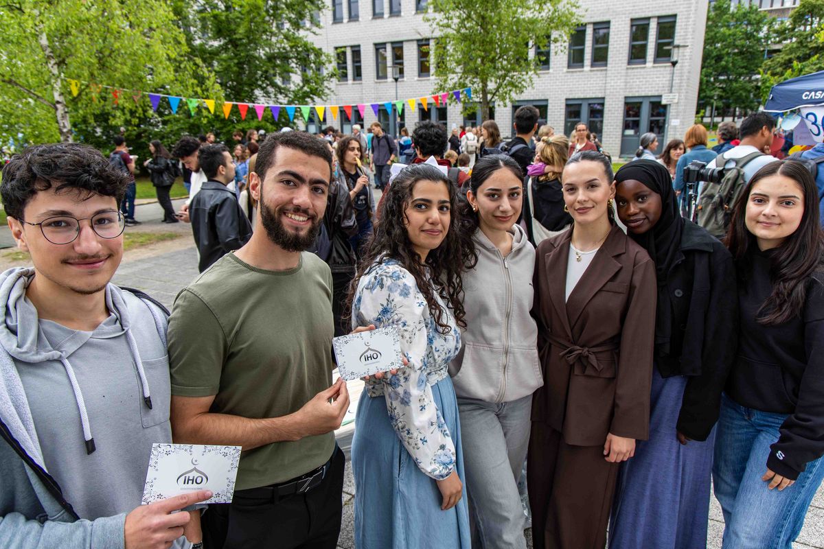 Glücklich wirkende Personen, die teilweise Postkarten der Islamischen Hochschulgruppe Oldenburg in die Kamera halten. 