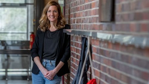 Foto der Erziehungswissenschaftlerin Anja Steinbach im Flur einer Schule. Sie lehnt an einer Wand aus roten Backsteinen, im Vordergrund sind Aufhänger für Jacken zu sehen.
