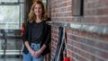 Foto der Erziehungswissenschaftlerin Anja Steinbach im Flur einer Schule. Sie lehnt an einer Wand aus roten Backsteinen, im Vordergrund sind Aufhänger für Jacken zu sehen.