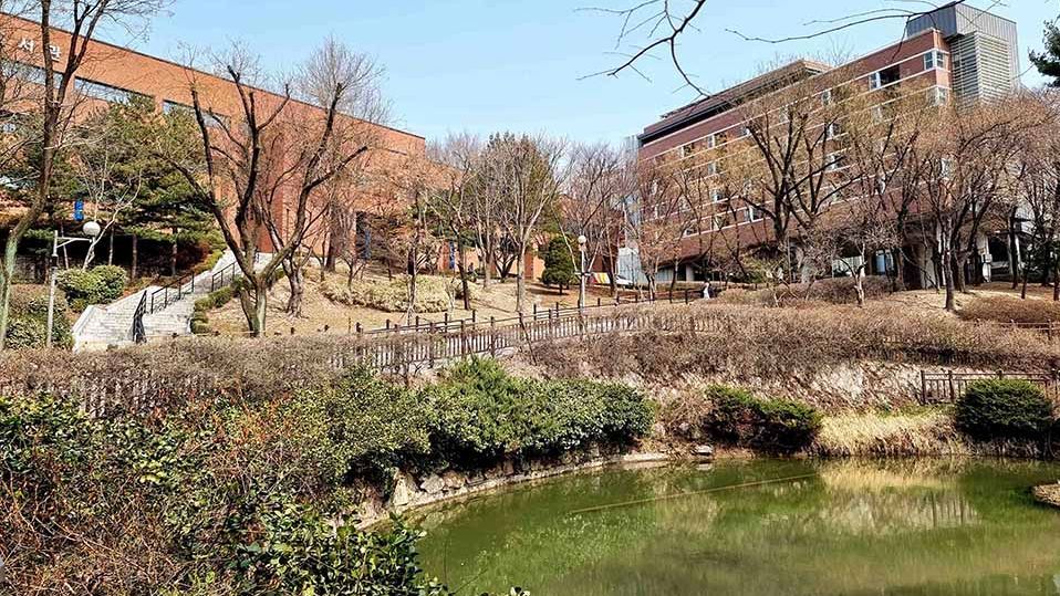 Campusteich University of Seoul Der Campusteich der University of Seoul mit grüner Vegetation und modernen Gebäuden im Hintergrund.