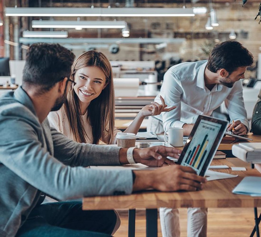 Gruppe junger, moderner Menschen, die bei der Arbeit im Büro kommunizieren und moderne Technologien nutzen