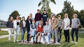Eine Gruppe junger Menschen sitzend und stehend auf dem Campus der Universität
