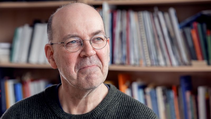 Das Bild zeigt Dietmar von Reeken. Er sitzt vor einem Bücherregal und schaut nachdenklich aus dem Fenster.