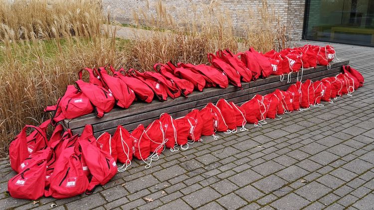 42 red backpacks lie on top of andin front of a bench near the experimental lecture hall in Wechloy.