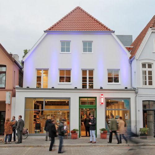 Das Bild zeigt das zweistöckige Schlaue Haus von der Rückseite. Es befindet sich in der Nähe des Schlosses Oldenburg. Die Rückseite ist weiß gestrichen.
