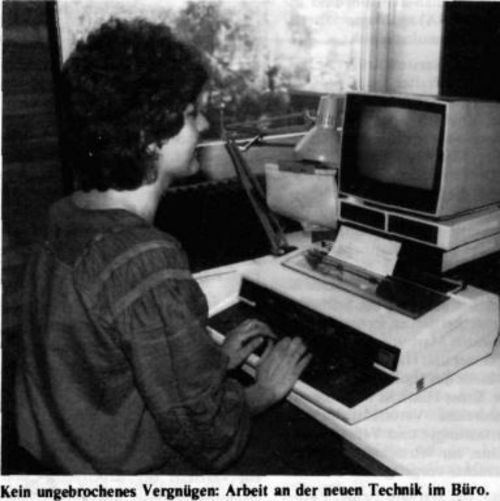 Das Bild zeigt eine Mitarbeiterin, die an einer Bildschirmschreibmaschine arbeitet. Die Bildunterschrift zu dem Foto aus Uni-Info lautet "Kein ungebrochenes Vergnügen: Arbeit an der neuen Technik im Büro".