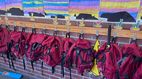 Praktikum im Ausland (Schule) Ein Klassenraum oder Flur in einer Schule mit kindlichen Malereien von Bergen und einem Sonnenuntergang. Darunter hängen rote Schultaschen mit Lamas und Kindernamen.