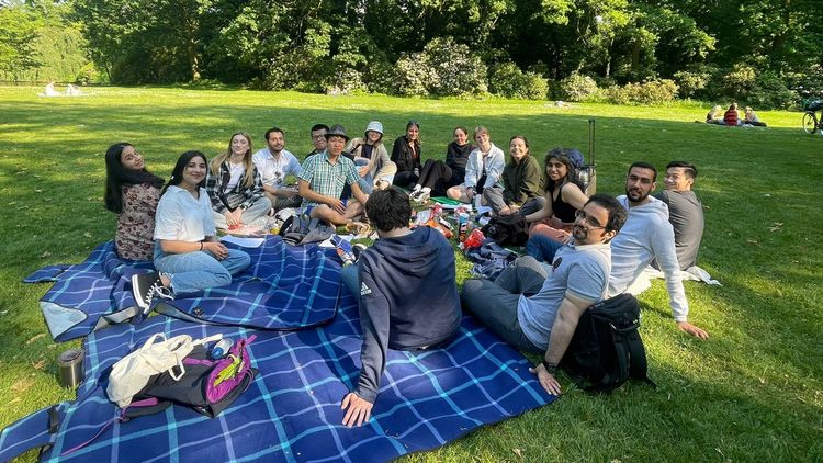 Cheer-Up-Meeting Eine Gruppe von Personen genießt ein Picknick oder eine Zusammenkunft in einem Park. Sie sitzen auf einer Decke und entspannen sich.