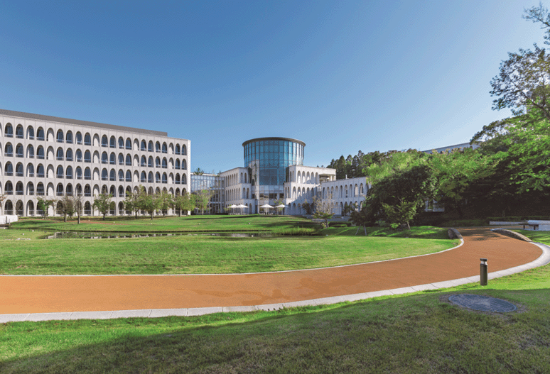 Toyota Campus Ein Universitätskomplex mit zwei Gebäuden und einer Rasenfläche mit roter Laufbahn.
