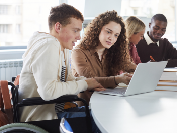 Vier Studierende sitzen am Tisch und lernen gemeinsam; die Studierenden sind weiblich und männlich, weiß und schwarz, ein Student sitzt im Rollstuhl